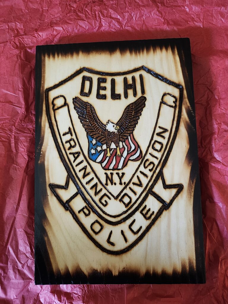 Burned wood plaque with eagle and flag and the words Delhi Police Training Division